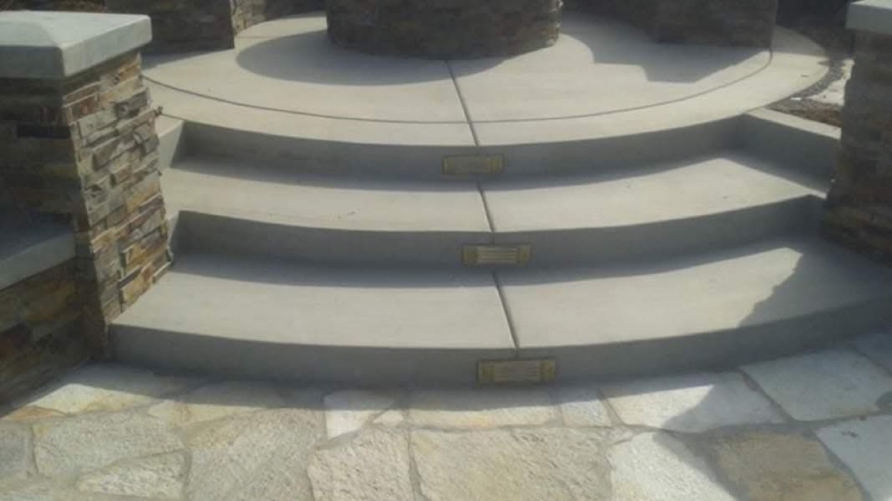 Curved smooth concrete steps flanked by stacked-stone columns