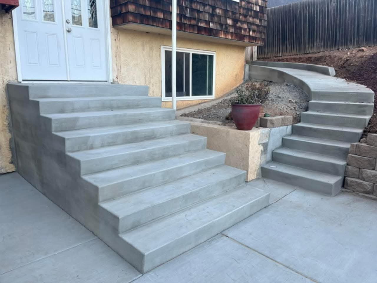 Two smooth poured-concrete staircases with a retaining wall