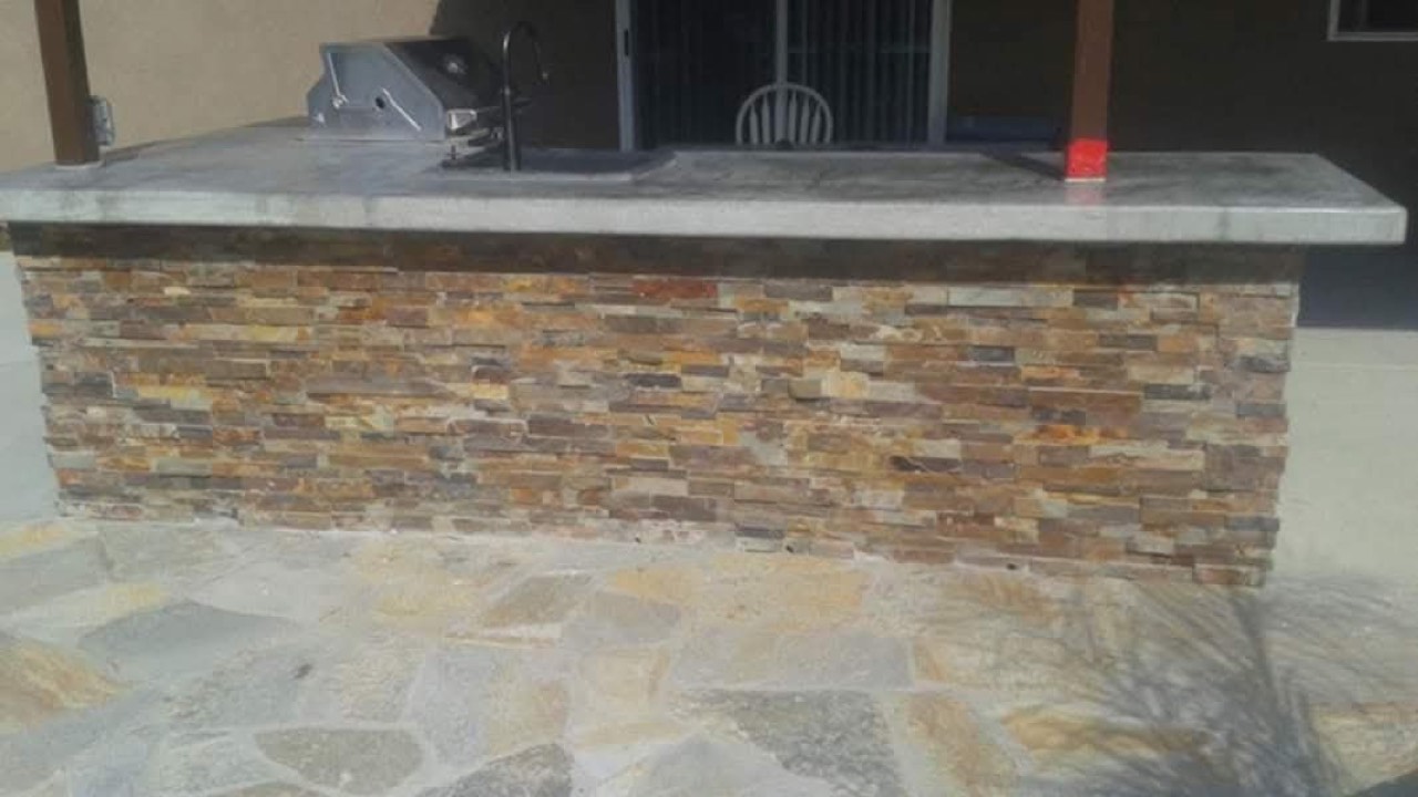 Outdoor kitchen BBQ island with stacked-stone facing and flagstone