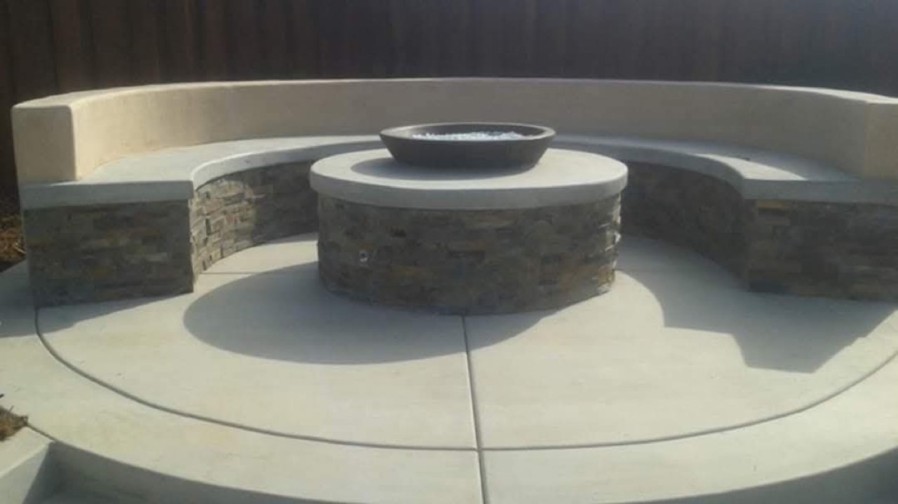 Concrete fire pit with a curved seat wall and stacked-stone facing