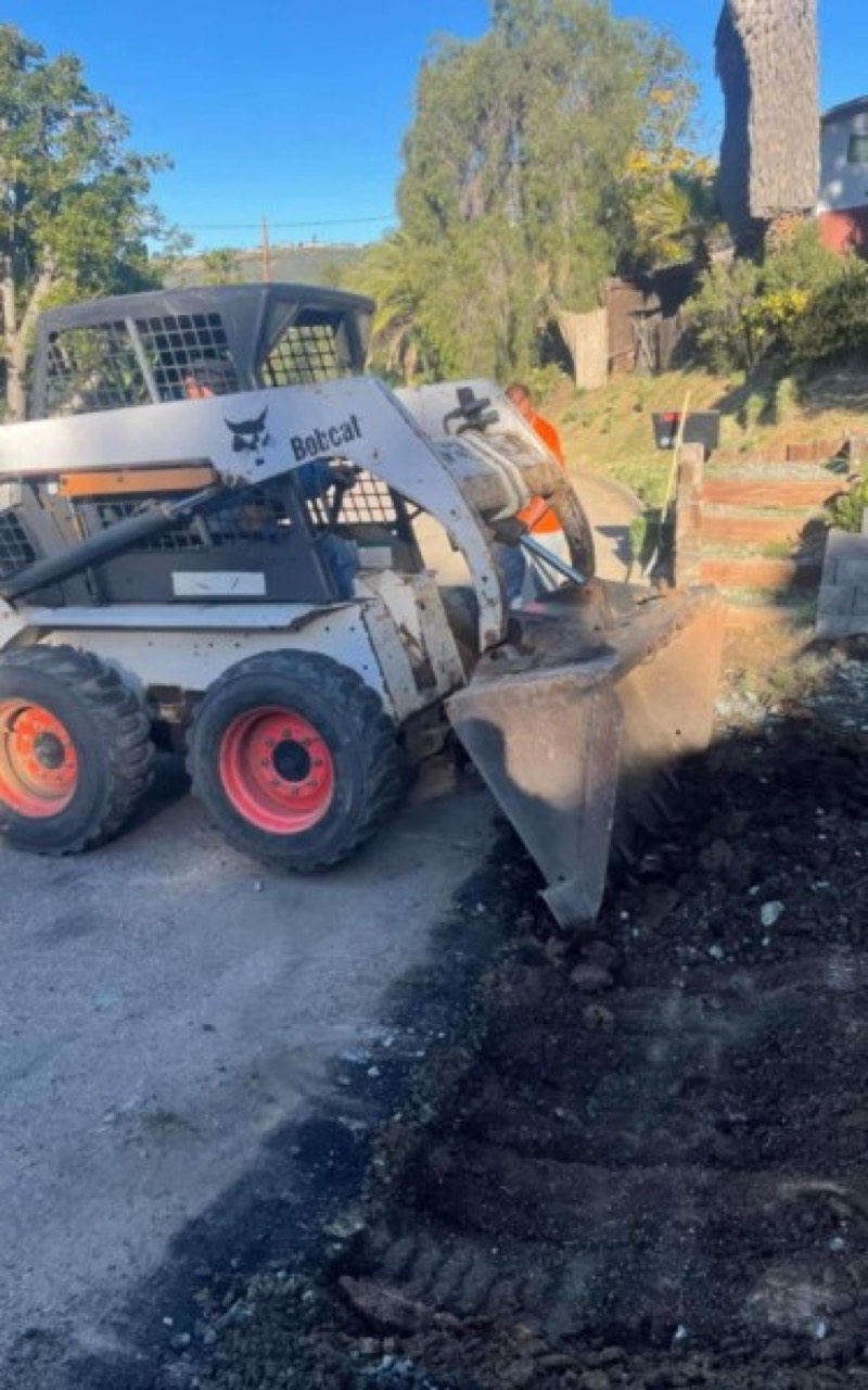 Bobcat skid steer removing old asphalt on a driveway job