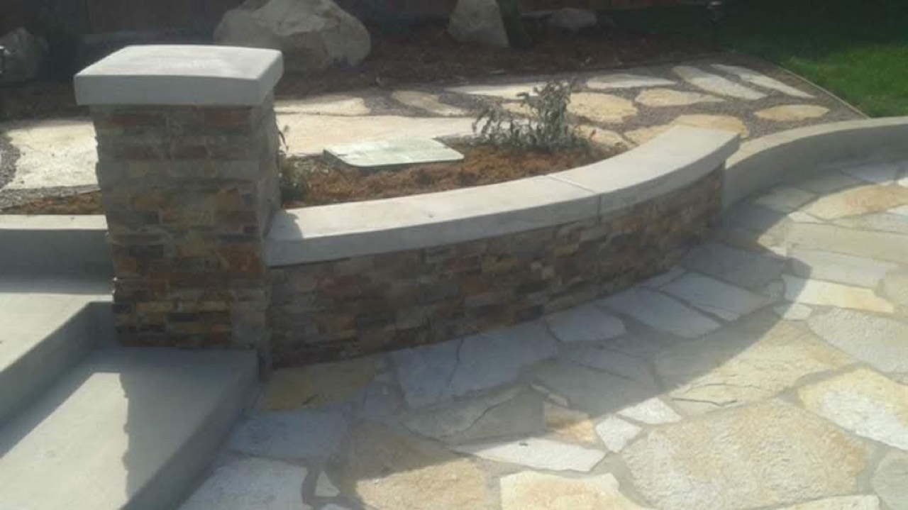 Flagstone patio with a curved stacked-stone seat wall and column
